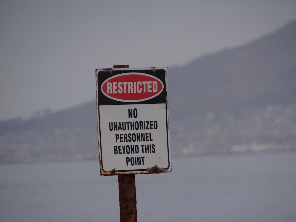 a warning sign posted on a pole near a body of water