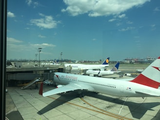 A panoramic shot of the Munich Airport runway with planes taxiing and the Alps in the background.