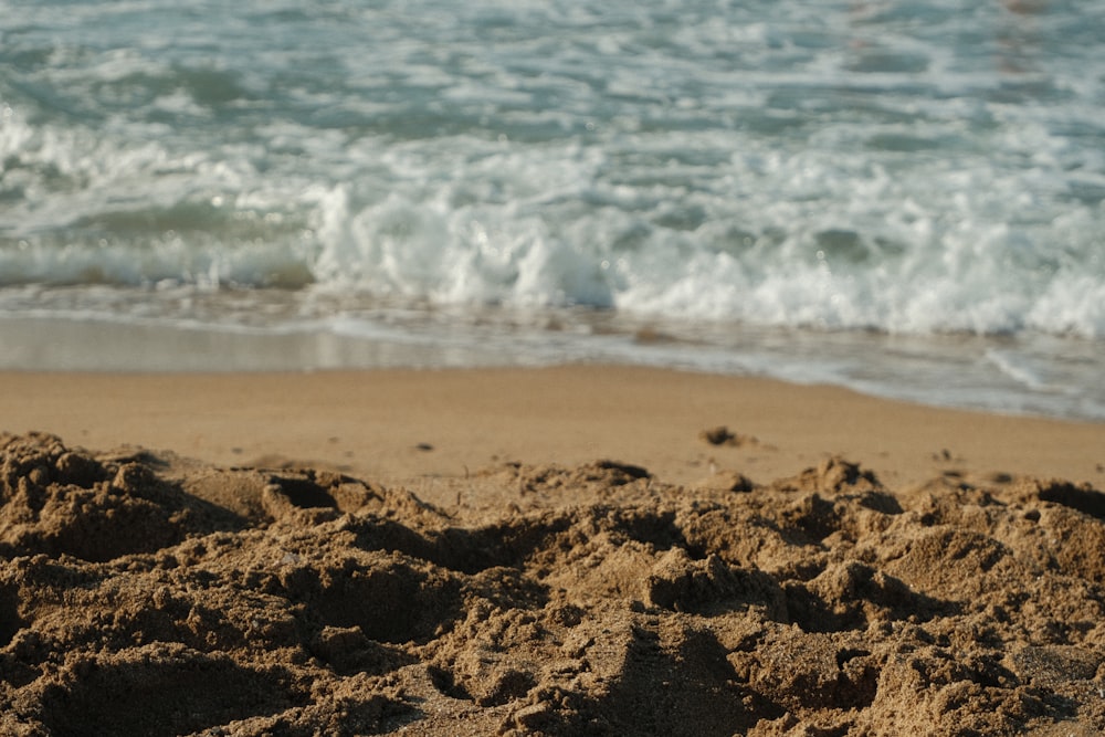 a sandy beach next to the ocean with waves coming in