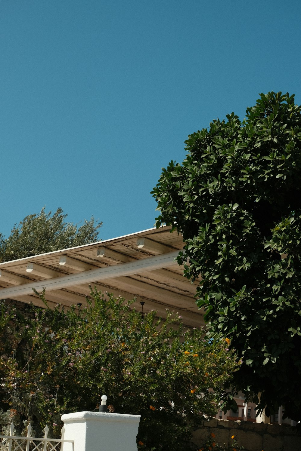 an airplane flying over a white fence and trees