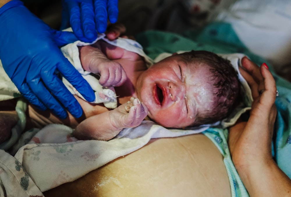 a person in blue gloves is holding a baby