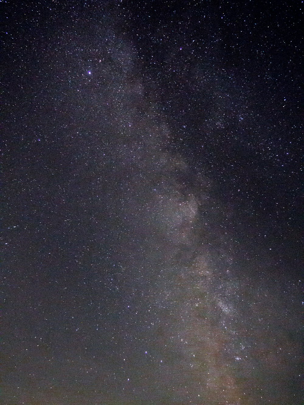 a group of people standing on top of a hill under a night sky filled with