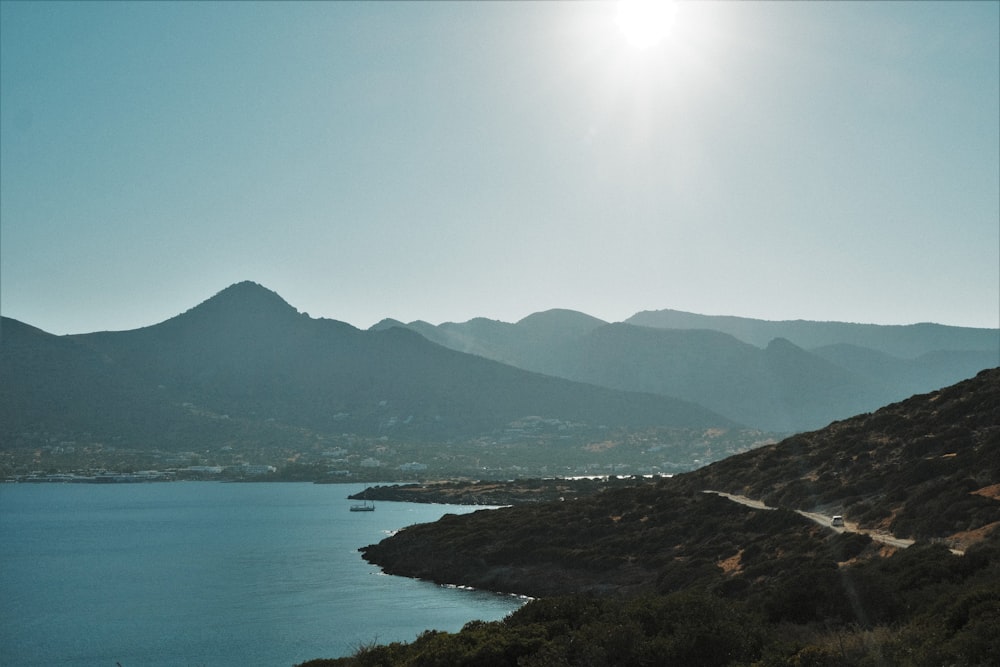 the sun is shining over the mountains and a body of water