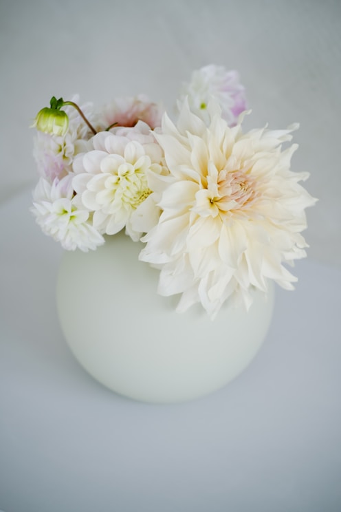 a white vase filled with white and pink flowers
