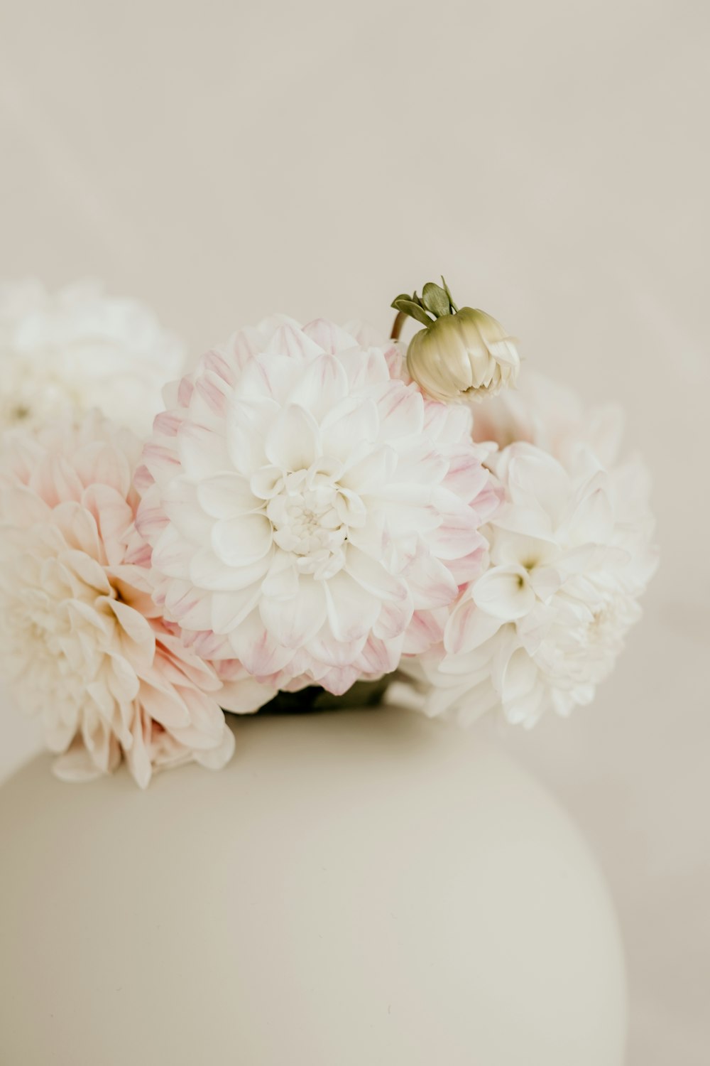 a white vase filled with pink and white flowers