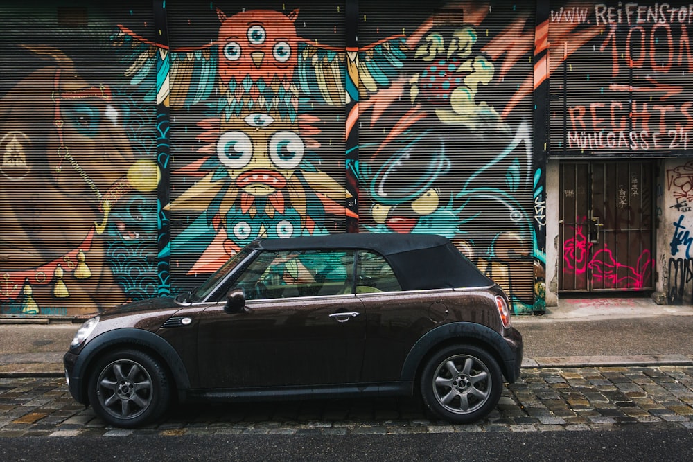 Une petite voiture garée devant un bâtiment couvert de graffitis