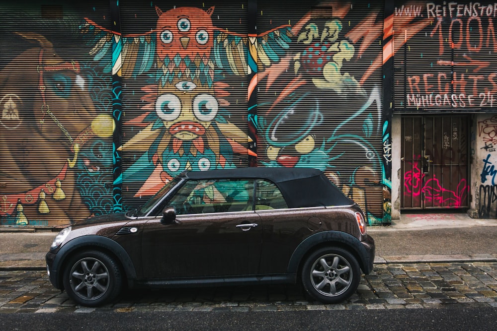 a small car parked in front of a graffiti covered building