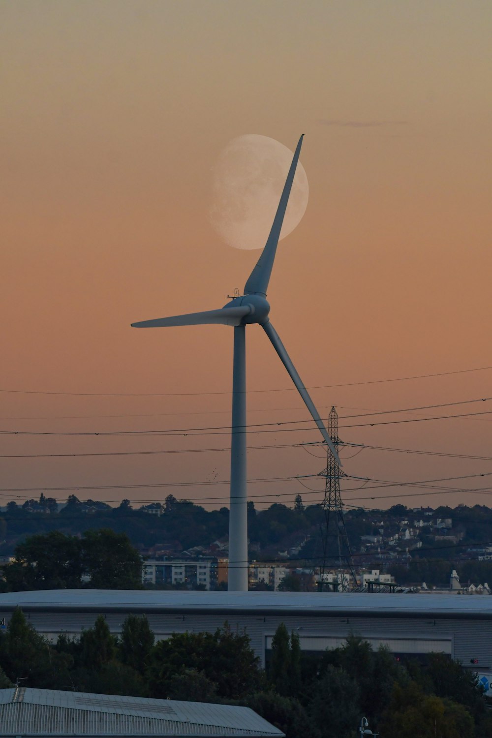 a wind turbine with a full moon in the background