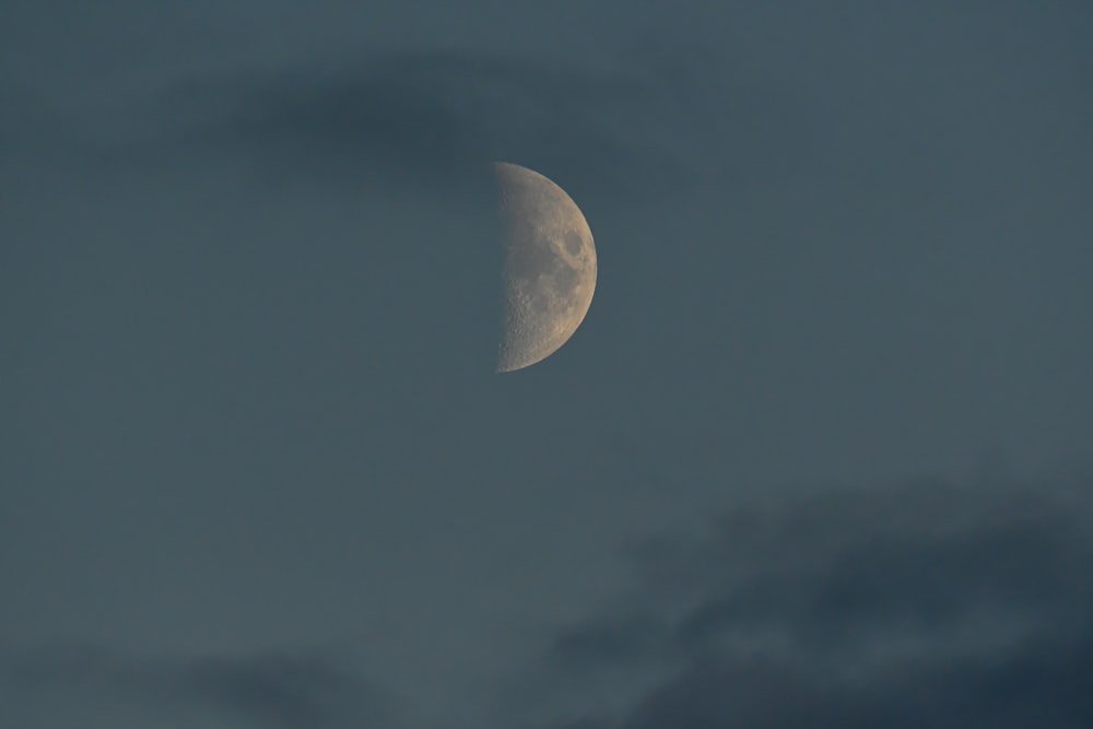 a half moon is seen through a cloudy sky
