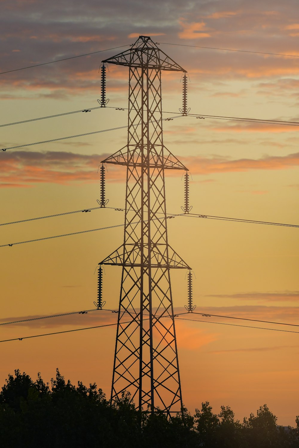 a high voltage power line with a sunset in the background