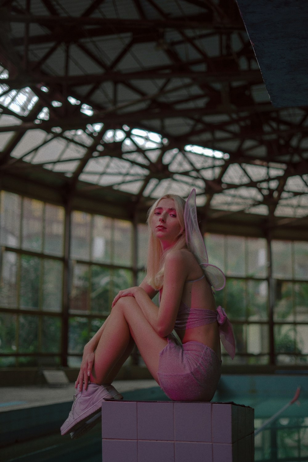 a woman sitting on top of a pink block next to a swimming pool