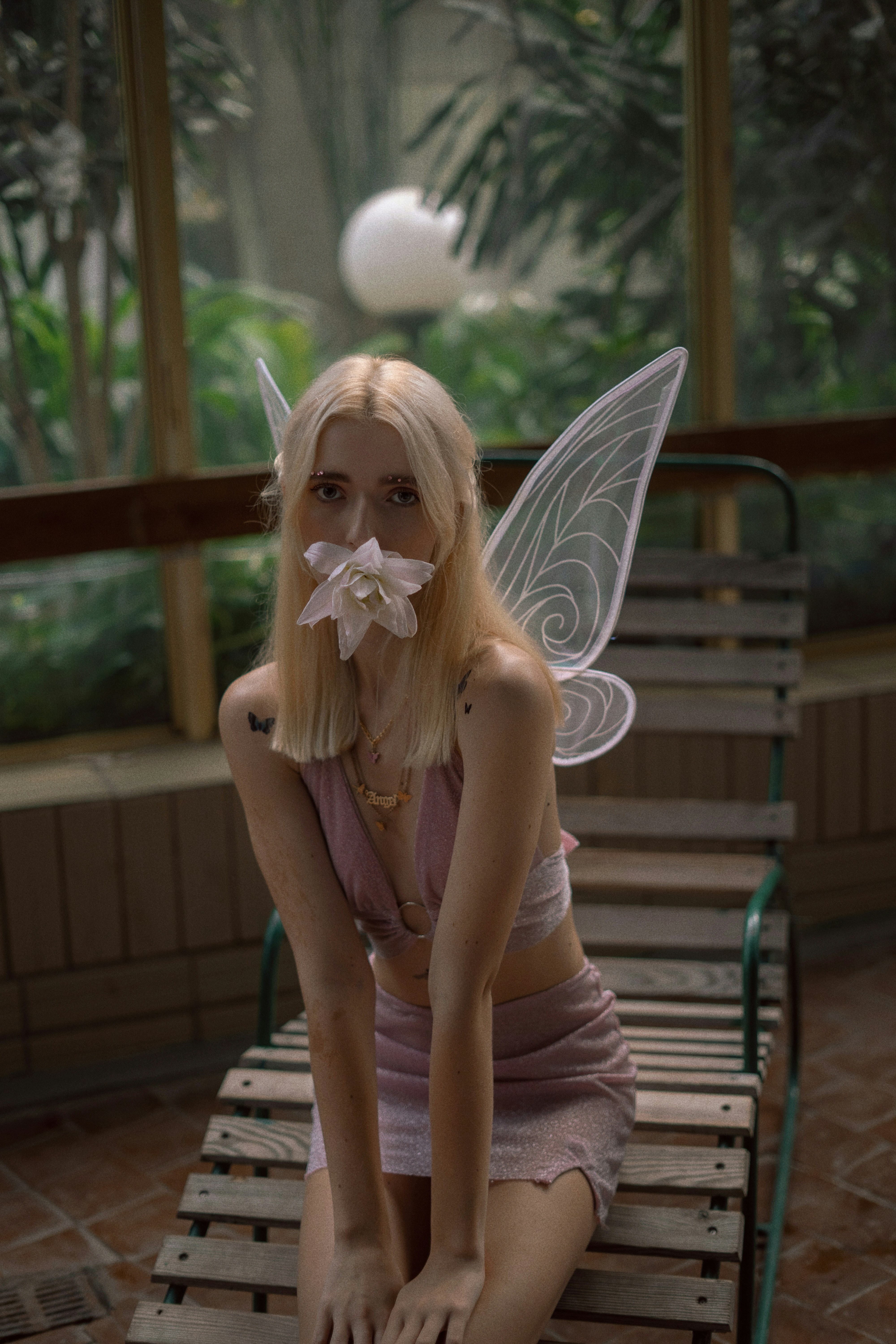 a woman sitting on a bench with a fake flower in her mouth