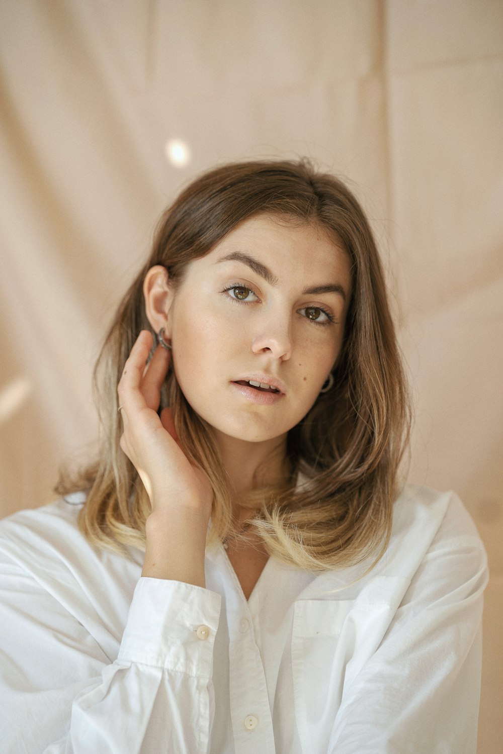 a woman in a white shirt is holding her ear