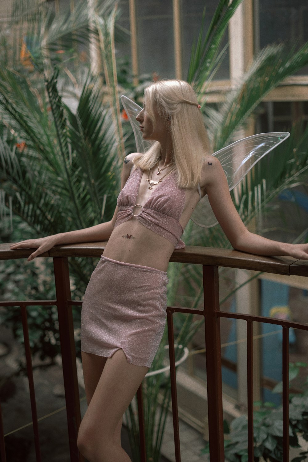 a woman in a pink dress is standing on a balcony