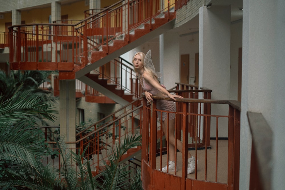 a woman standing on a balcony next to a spiral staircase