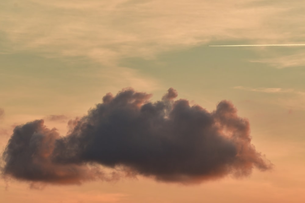 a plane flying in the sky with a cloud in the foreground