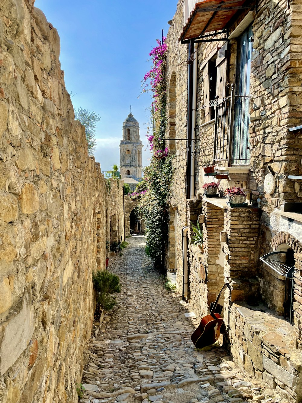 a cobblestone street with a guitar leaning against a stone wall