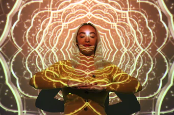 a woman in a yellow outfit is standing in front of a glowing background