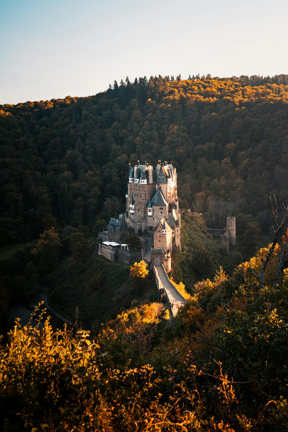 Un grande castello seduto sulla cima di una collina verde lussureggiante