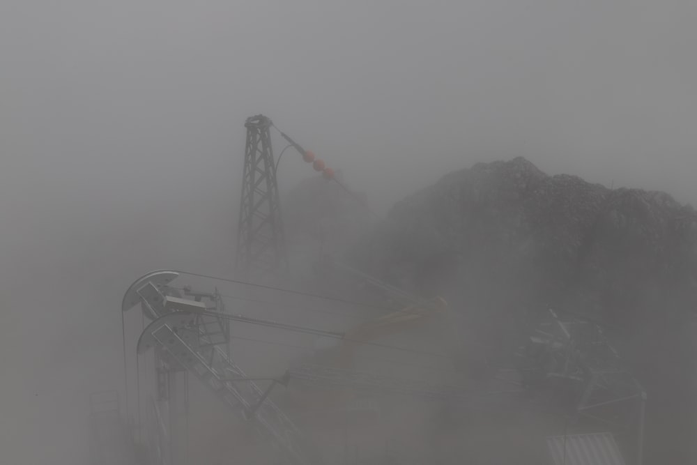 a large metal structure in the middle of a foggy field
