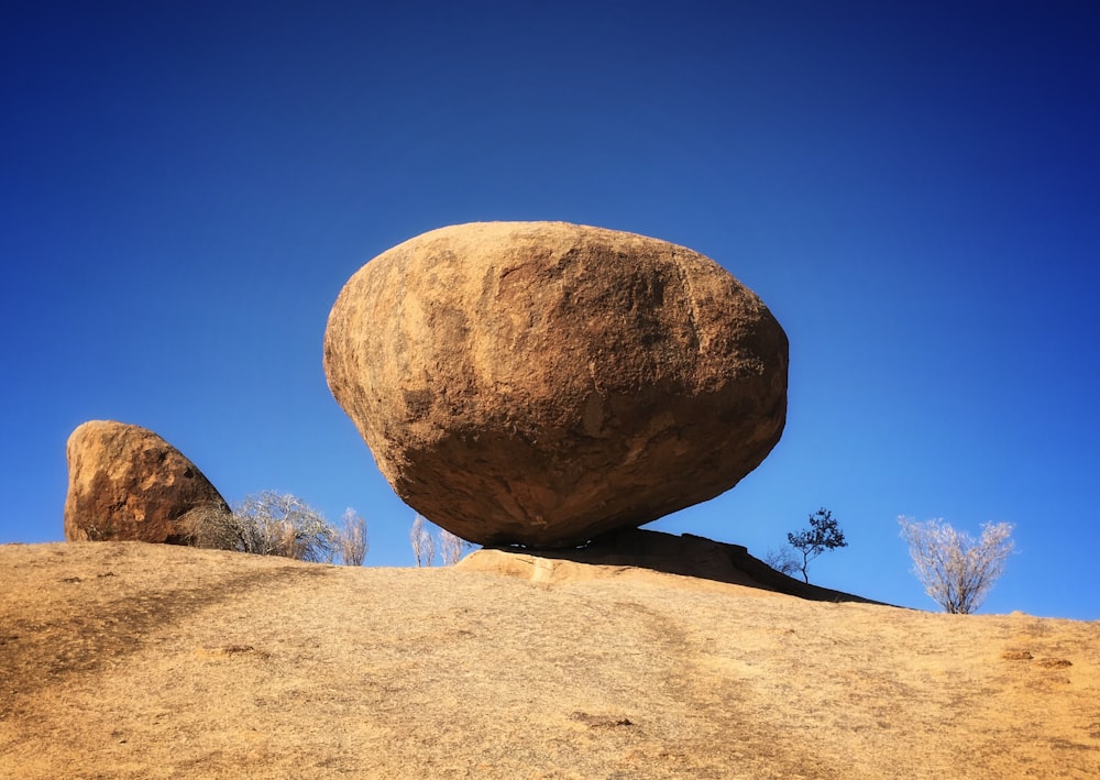 a large rock sitting on top of a dry grass field