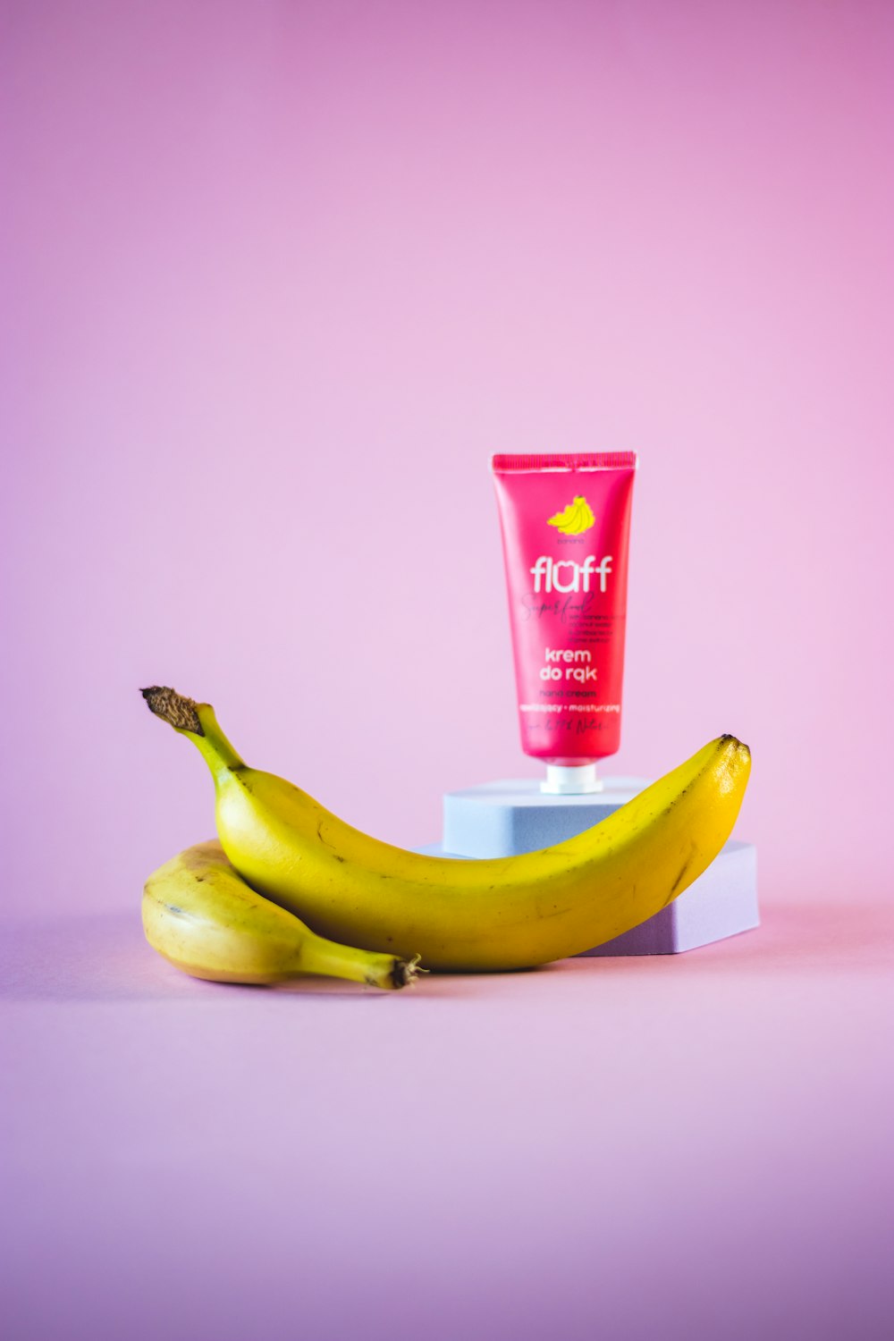 a banana and a tube of sunscreen on a pink background
