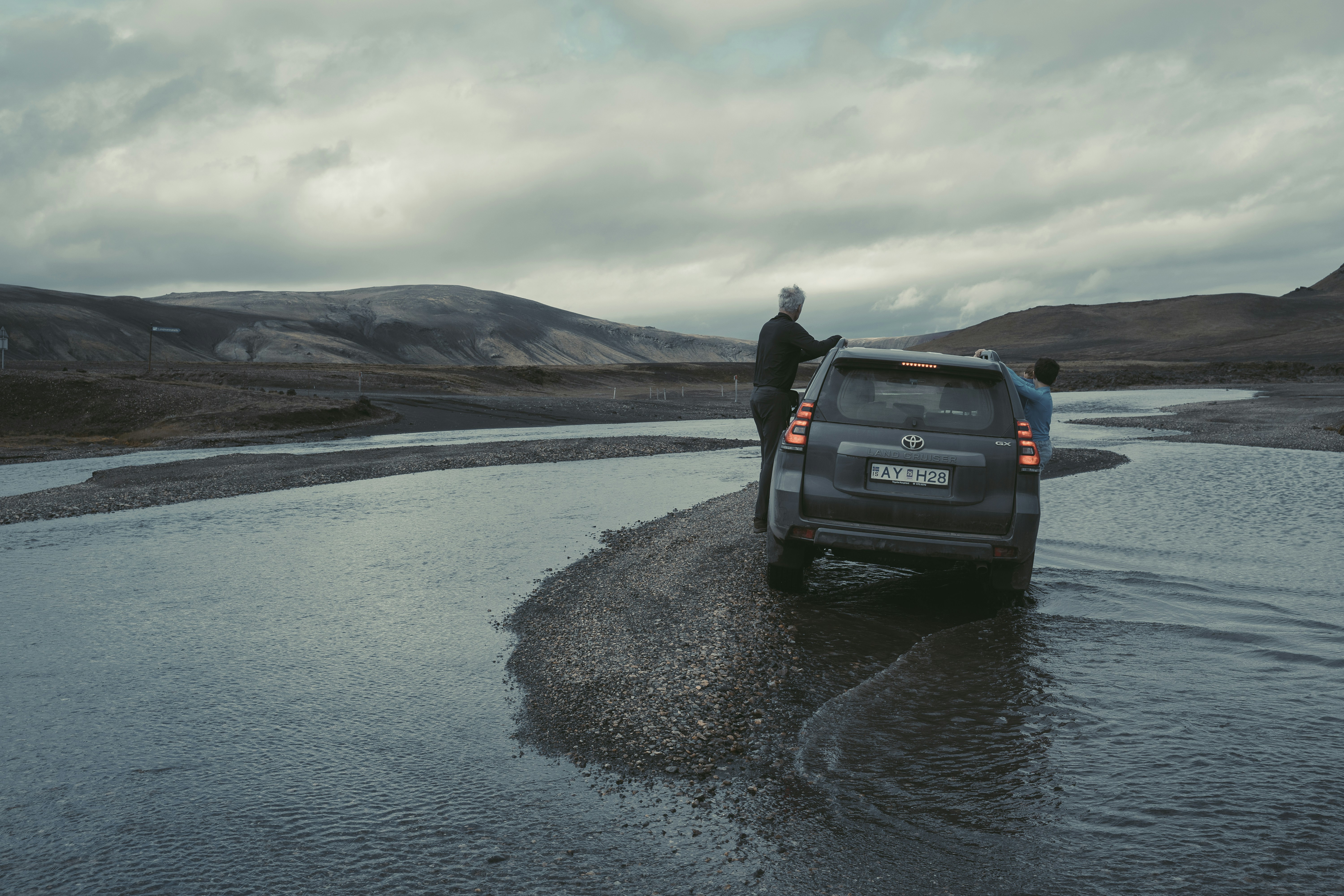 a man standing next to a car in a body of water