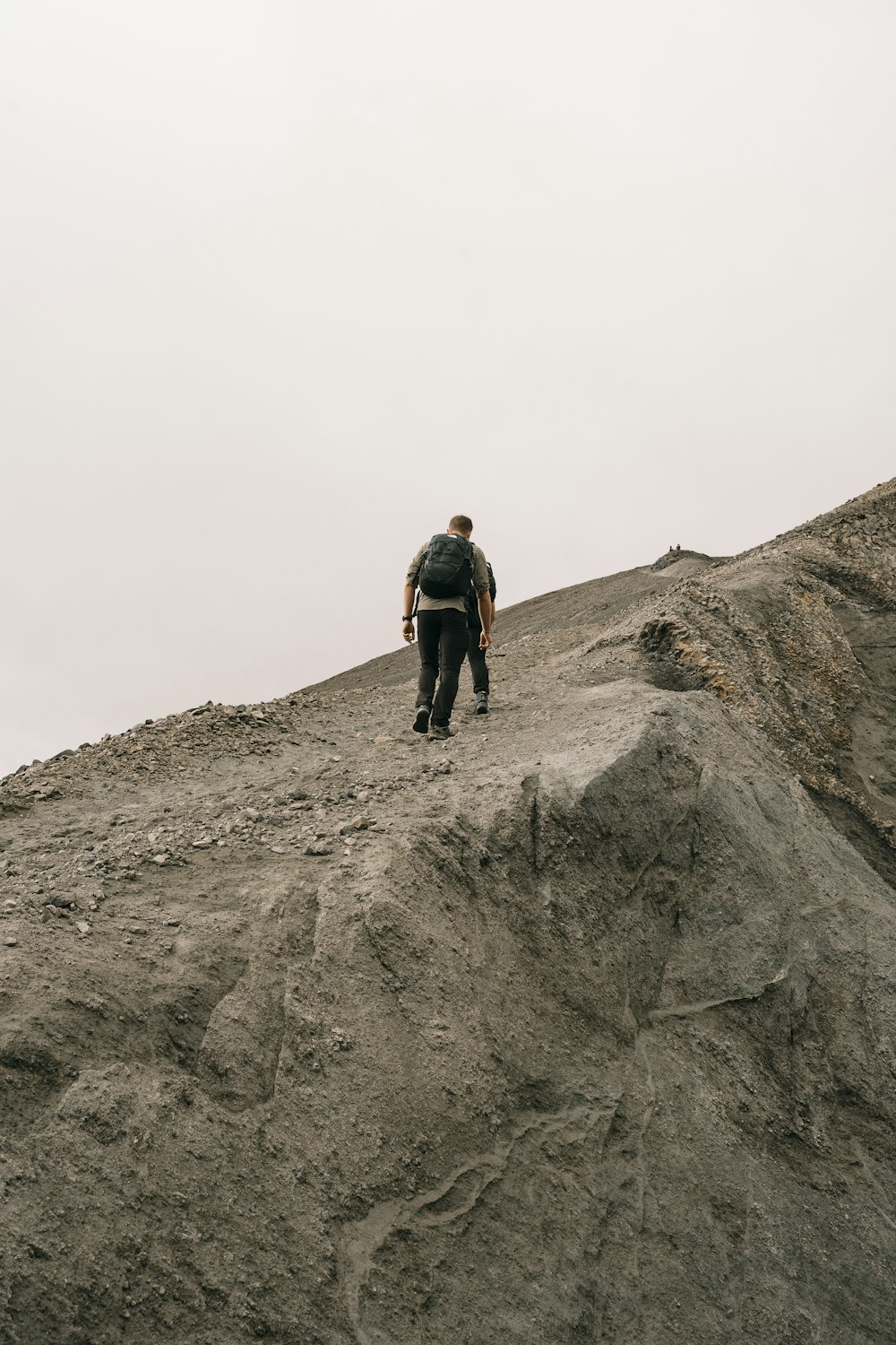 a man walking up a hill on a cloudy day