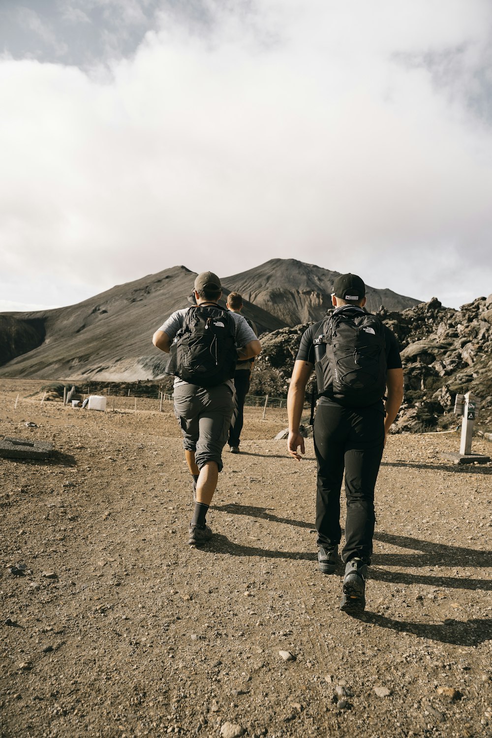 a couple of men walking across a dirt field