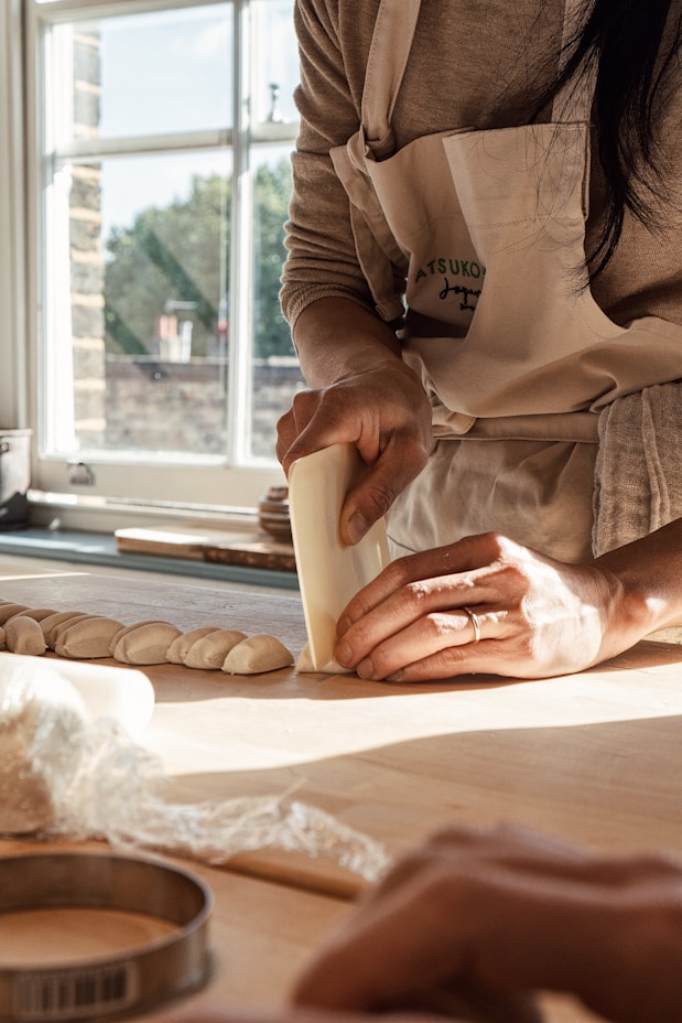 A skilled baker shaping fresh dough in a rustic, sunlit bakery kitchen.