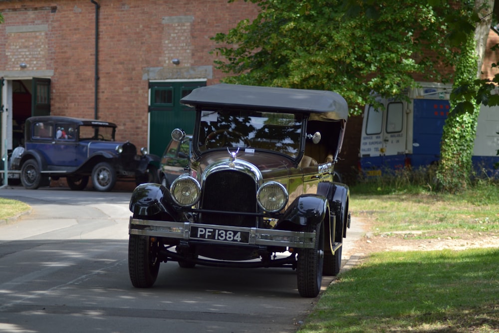 a vintage car driving down a street next to a brick building