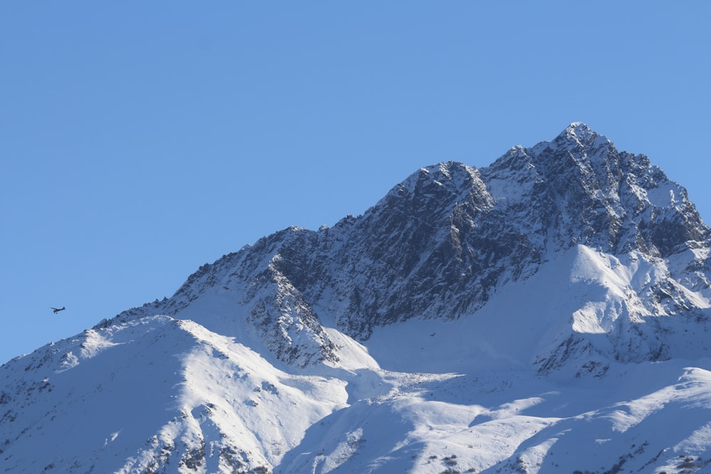 a large mountain covered in snow under a blue sky