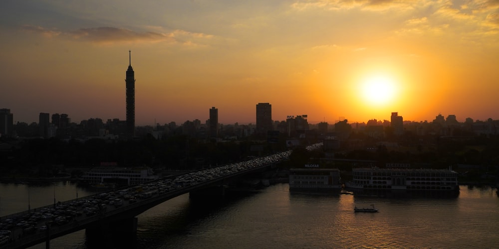 the sun is setting over a city with a bridge