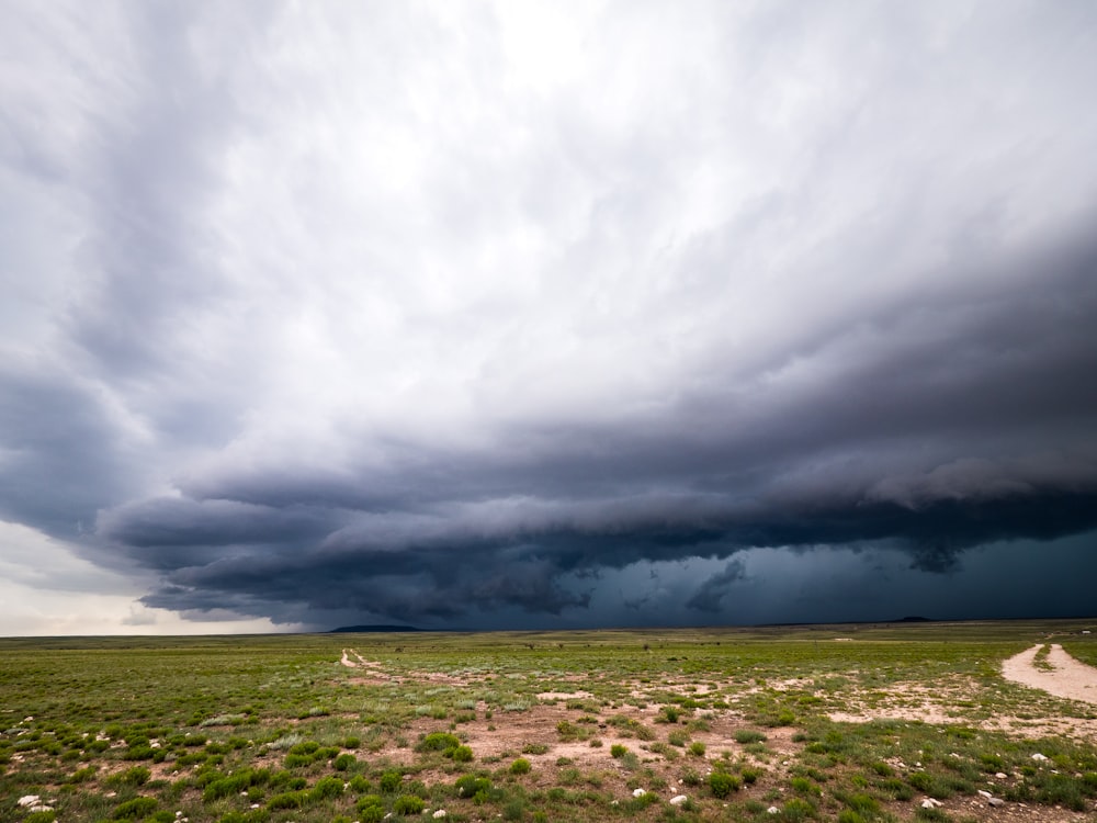 a storm moving through the sky over a dirt road