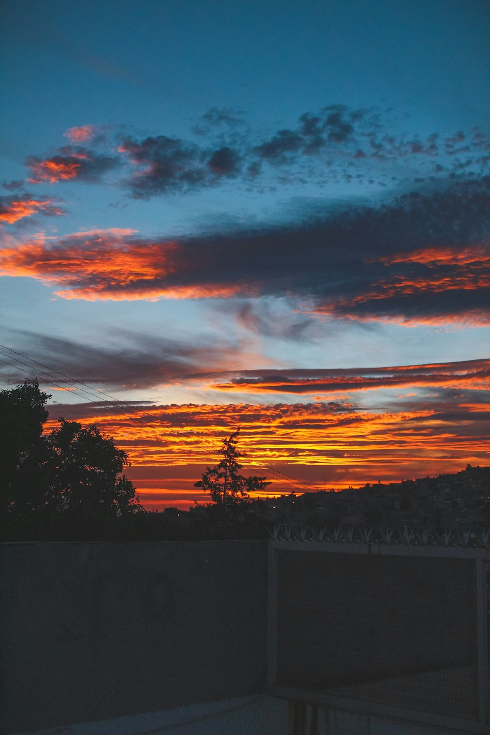 a sunset with clouds and trees in the background