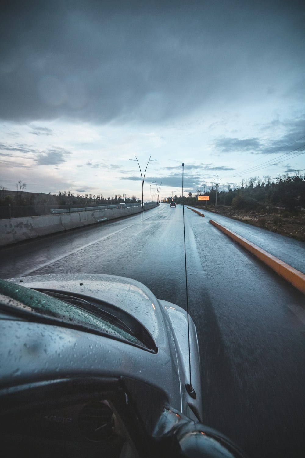a car driving down a wet road under a cloudy sky