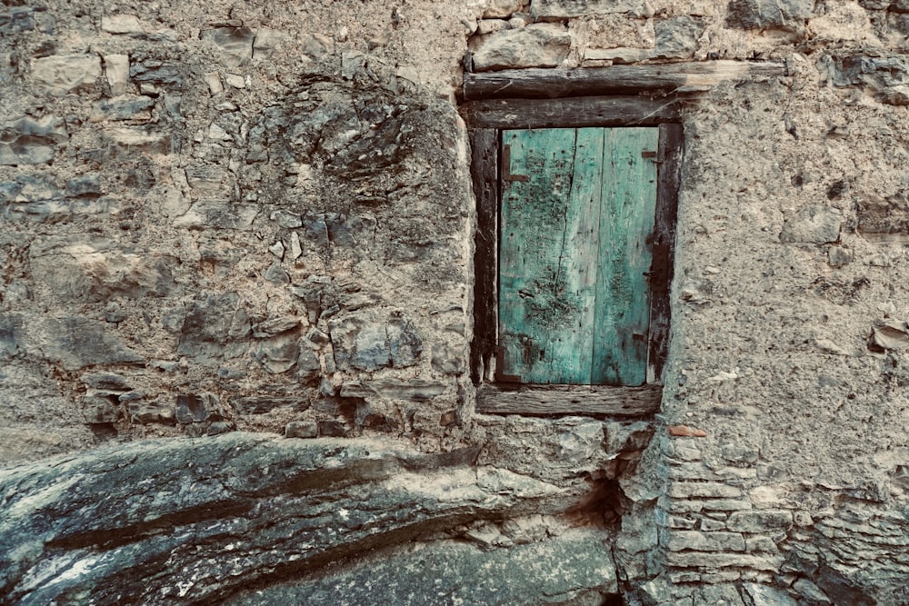 a window in a stone building with a green door