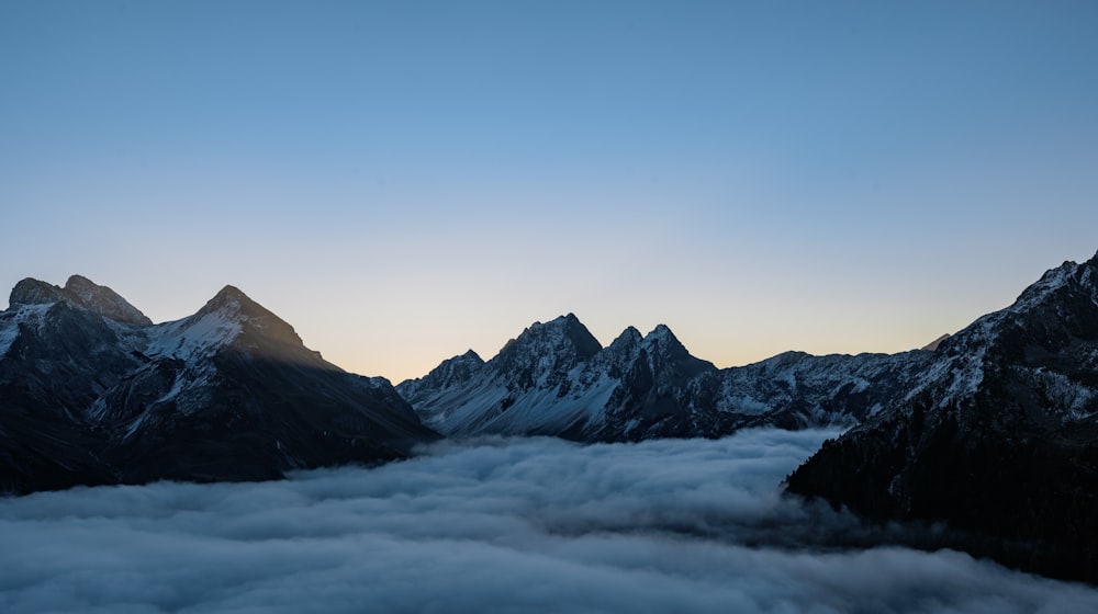 a view of a mountain range with clouds below