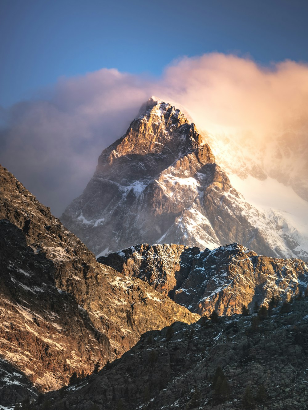 Una montagna coperta di neve con le nuvole nel cielo