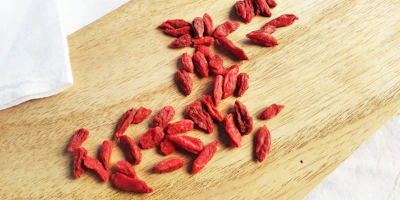 Bright red goji berries spilling from a small ceramic bowl.