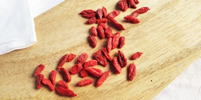 Close-up of fresh goji berries and assorted nuts spilling from a natural fiber bag.