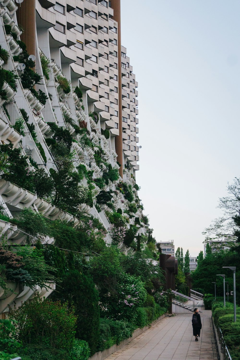 a man walking down a sidewalk next to a tall building