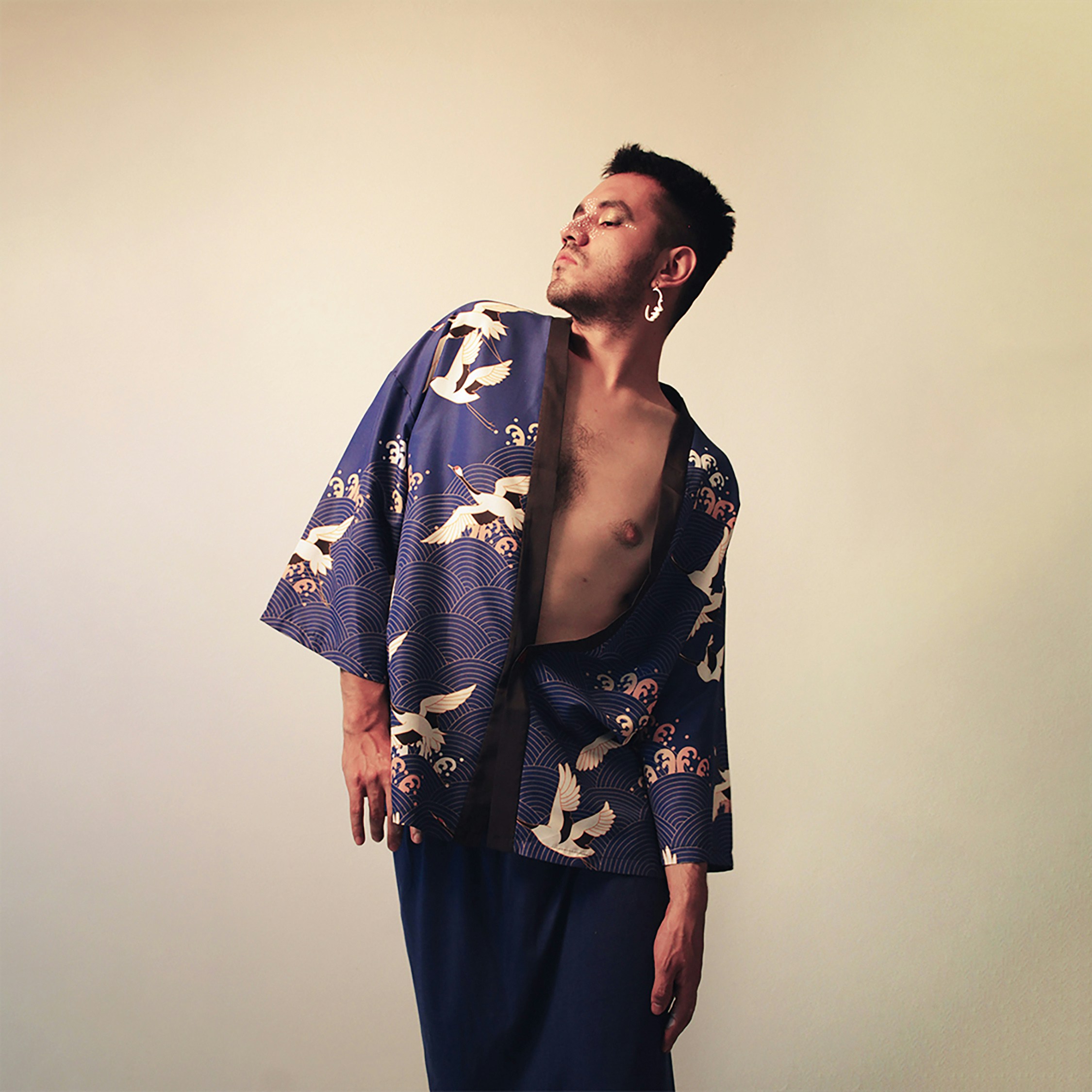 a man in a blue kimono standing in front of a white wall
