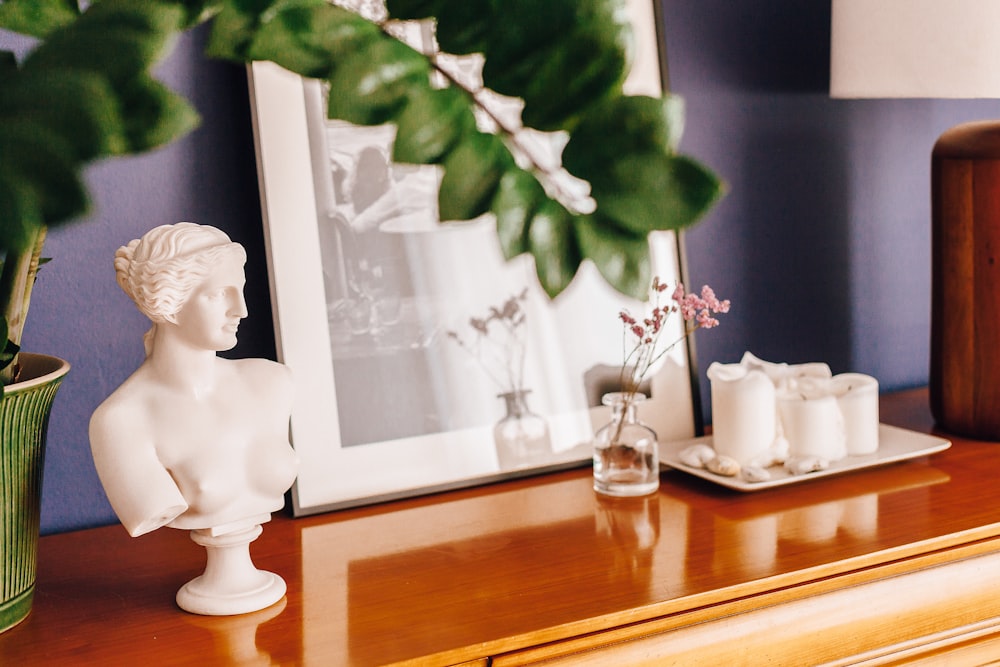 a white statue sitting on top of a wooden dresser