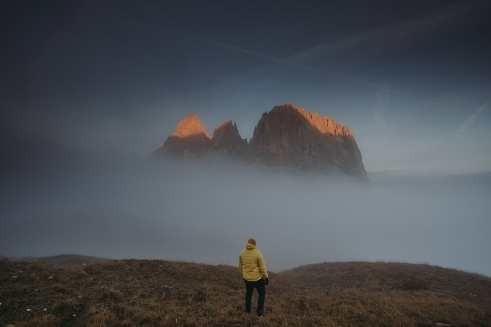 a person standing on top of a grass covered hill