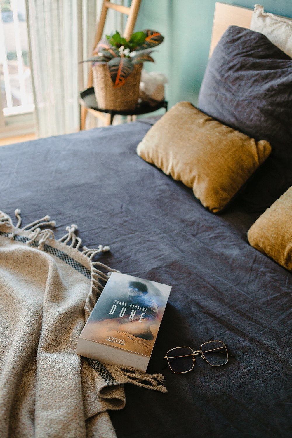 a book on a bed next to a pair of glasses