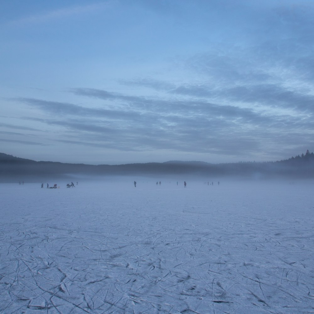 um grupo de pessoas em pé em cima de um campo coberto de neve