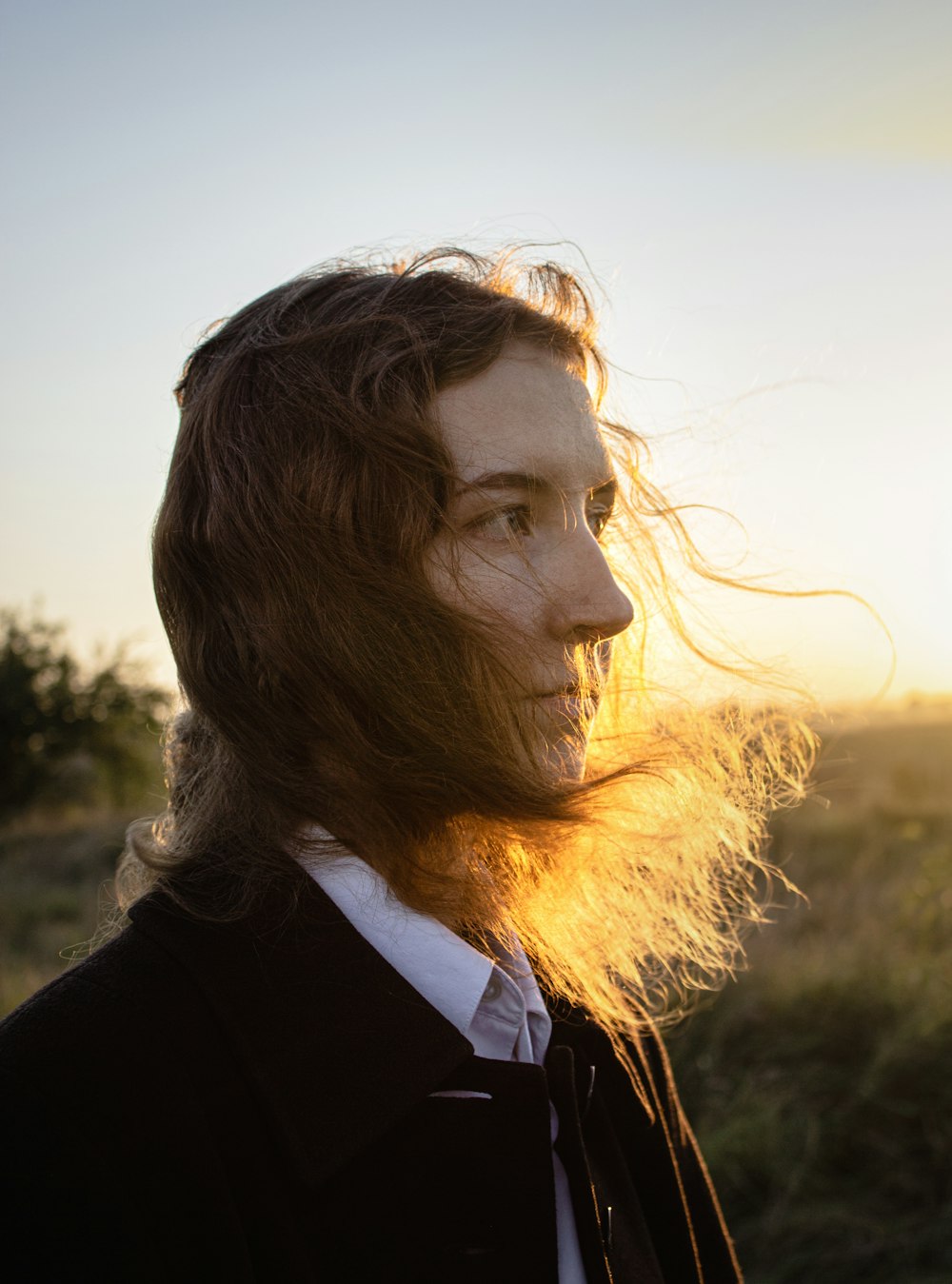 a man with long hair standing in a field