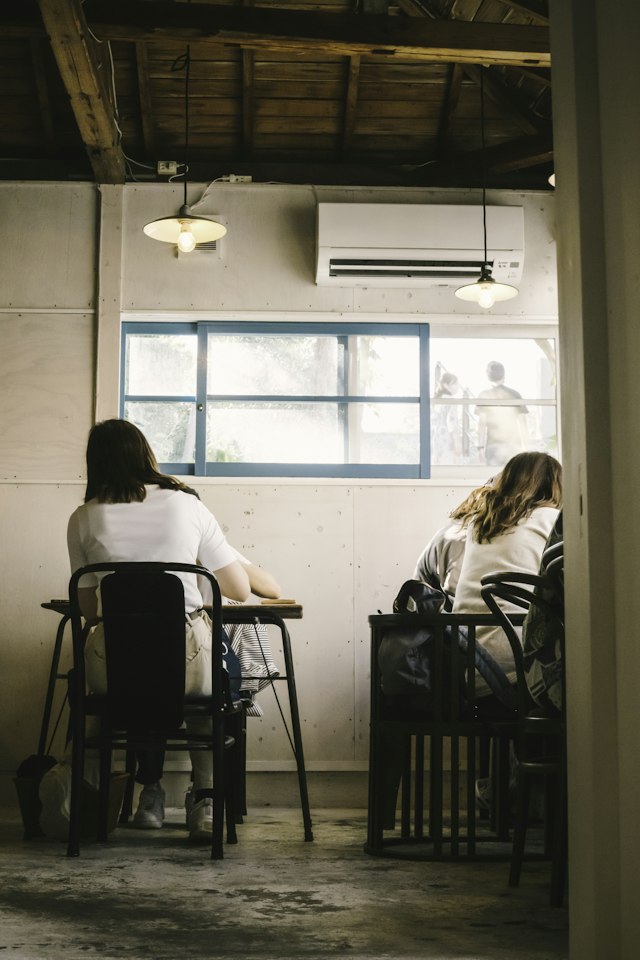 Two friends sitting at a table by a window