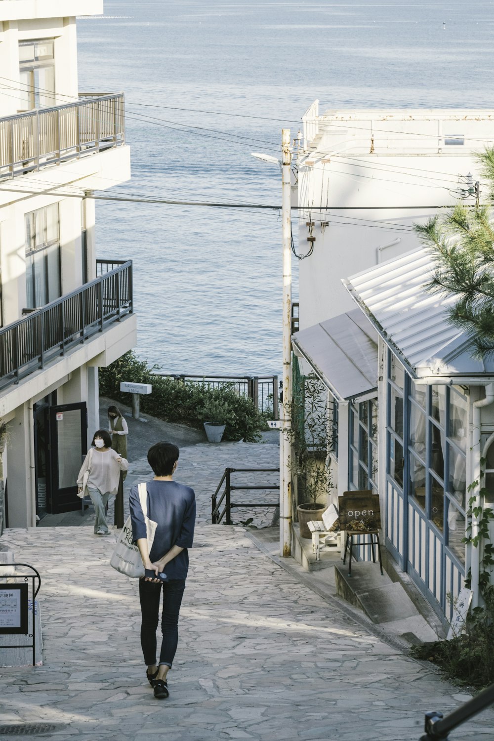 a man walking down a street next to a body of water